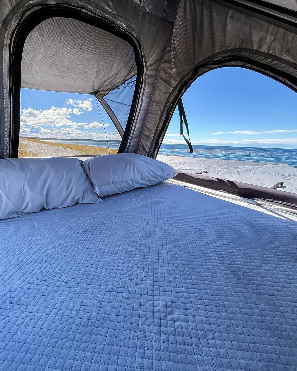 Interior de la carpa rooftop Outbase Overland con vista a la playa