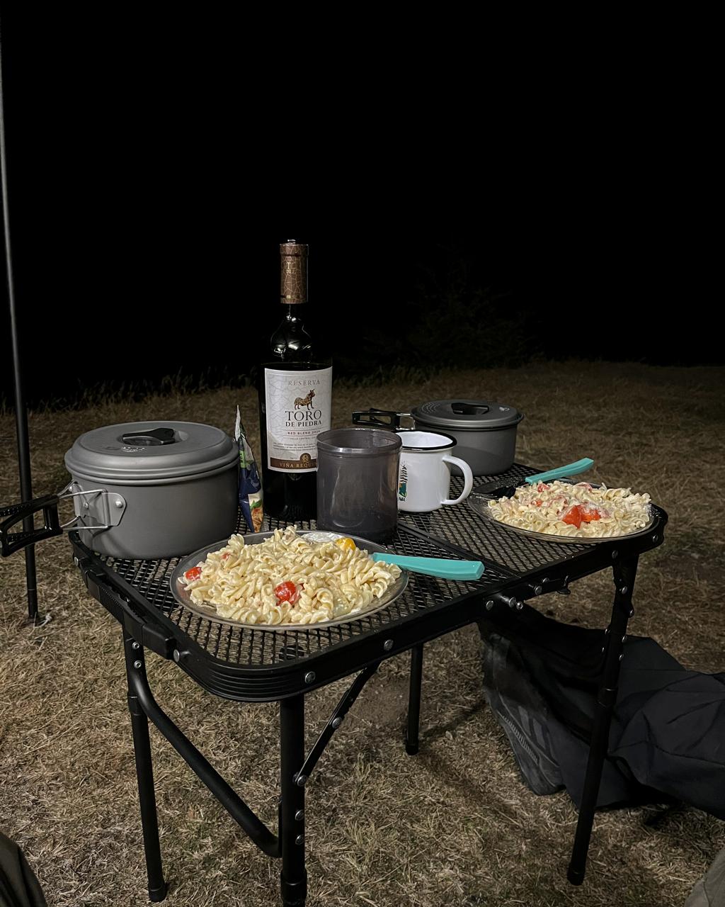 Cena de pasta y vino junto al camper, de noche