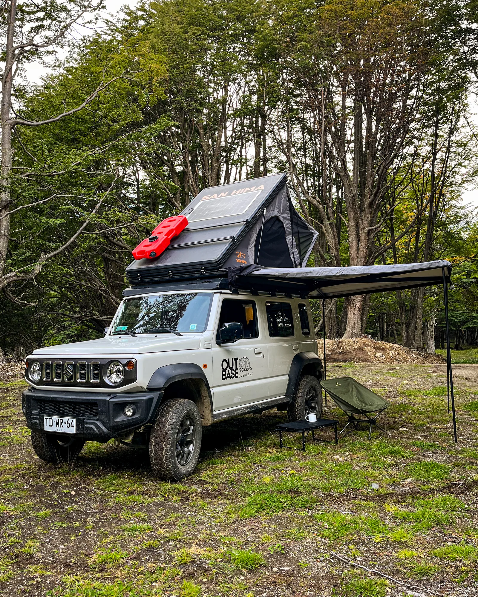 Camper Outbase Overland con carpa rooftop y toldo desplegados en el bosque