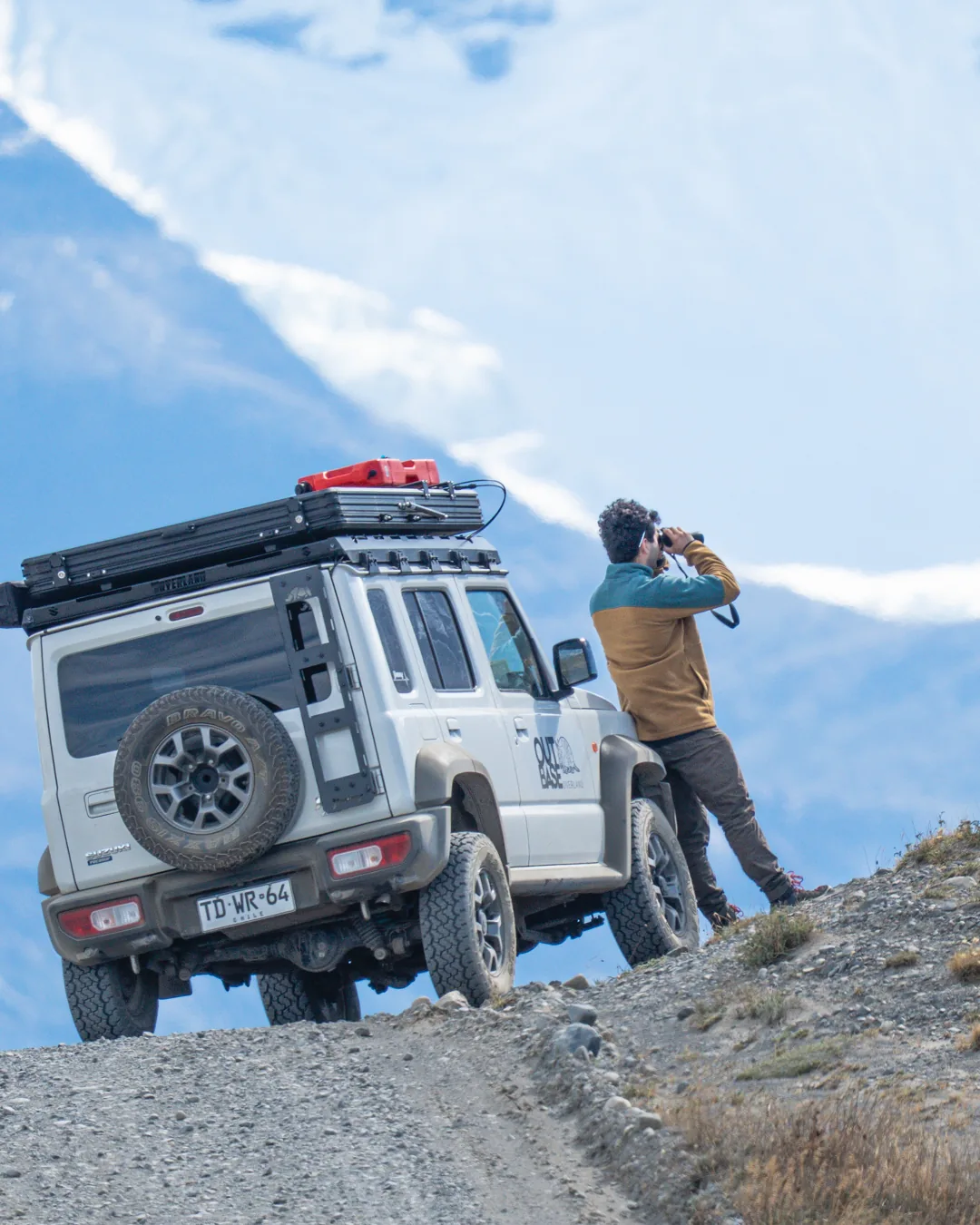 Viajero observando la cordillera con binoculares junto al camper