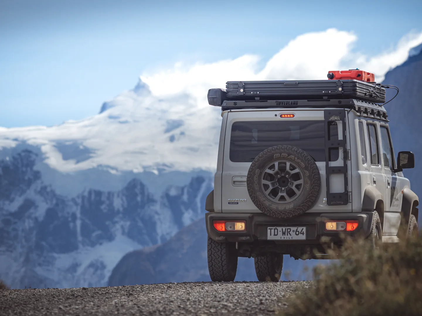 Camper Outbase coronando un camino de ripio con la cordillera de fondo