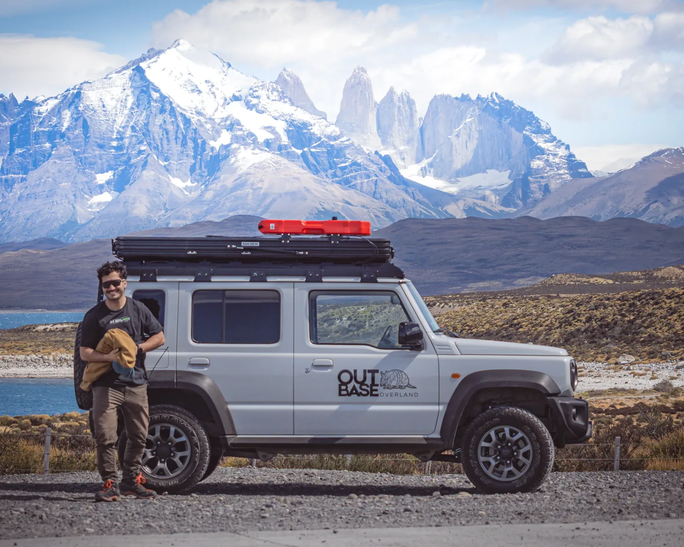 Viajero junto al camper Outbase con las Torres del Paine de fondo
