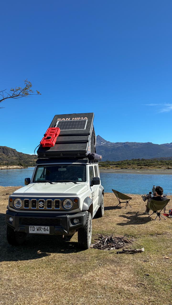 Camper Outbase junto a un lago, con panel solar desplegado