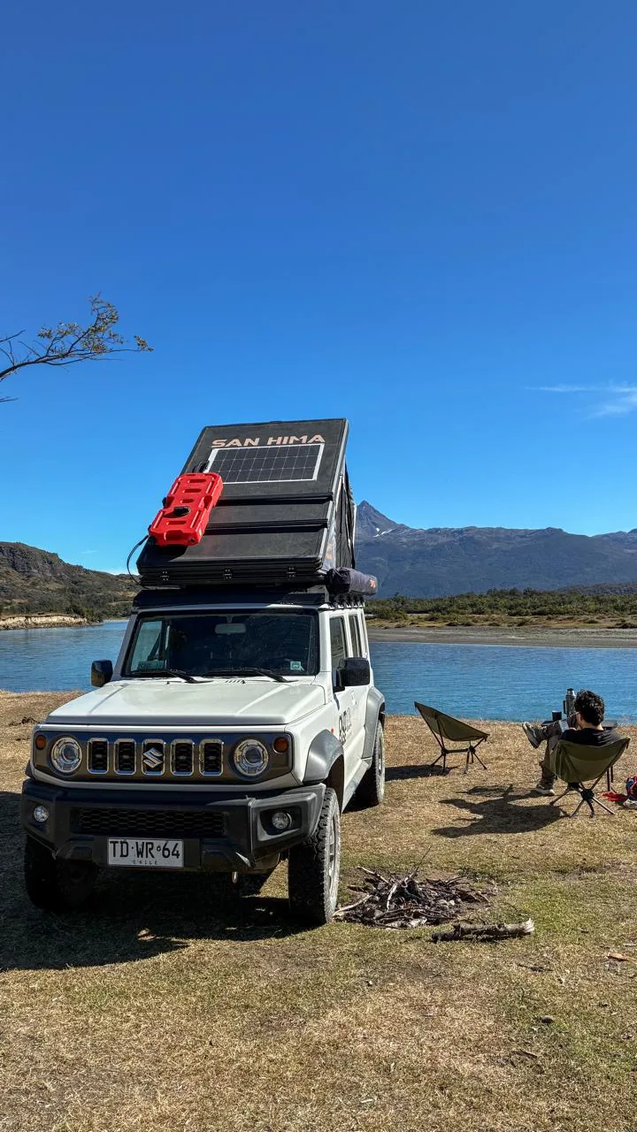 Camper Outbase junto a un lago, con panel solar desplegado